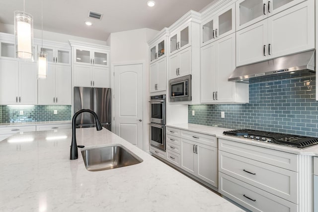 kitchen featuring visible vents, under cabinet range hood, decorative light fixtures, appliances with stainless steel finishes, and a sink