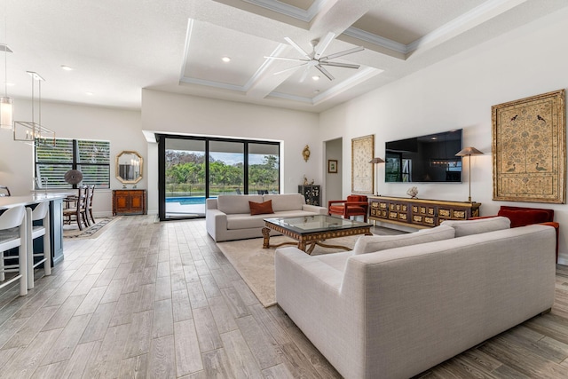 living area featuring wood finished floors, coffered ceiling, a healthy amount of sunlight, and a towering ceiling