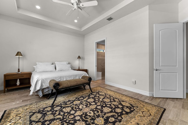 bedroom with baseboards, visible vents, a tray ceiling, light wood-style flooring, and recessed lighting