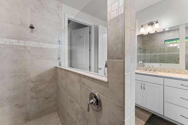 bathroom featuring walk in shower, wood finished floors, and vanity