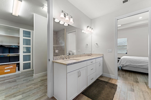 ensuite bathroom with a sink, wood tiled floor, and ensuite bathroom