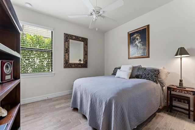 bedroom featuring light wood-style flooring, baseboards, and ceiling fan