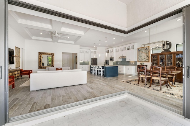 living room with crown molding, ceiling fan, recessed lighting, a towering ceiling, and coffered ceiling