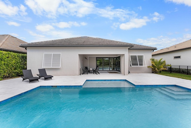 rear view of property with stucco siding, a patio, fence, a fenced in pool, and a tiled roof