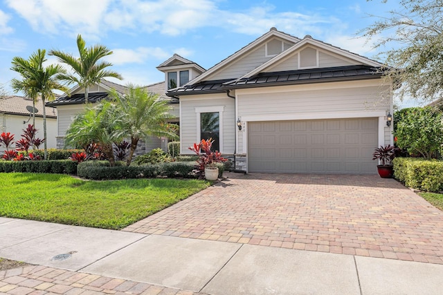 view of front of home with a standing seam roof, decorative driveway, metal roof, a front yard, and a garage