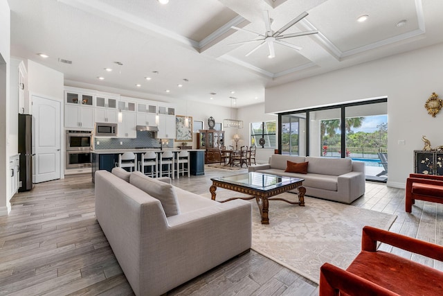 living area with visible vents, light wood-style flooring, coffered ceiling, and a ceiling fan