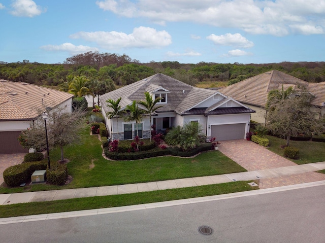 view of front of house with stone siding, an attached garage, decorative driveway, and a front lawn