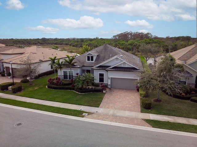 view of front of property featuring a garage, a tile roof, decorative driveway, and a front lawn