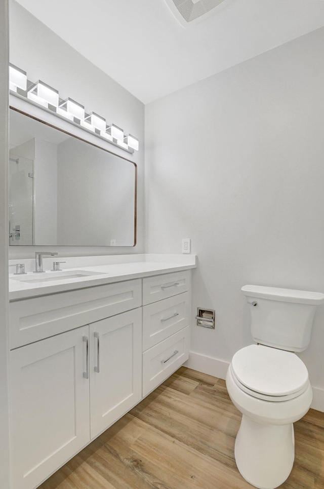 bathroom featuring vanity, hardwood / wood-style flooring, toilet, and walk in shower