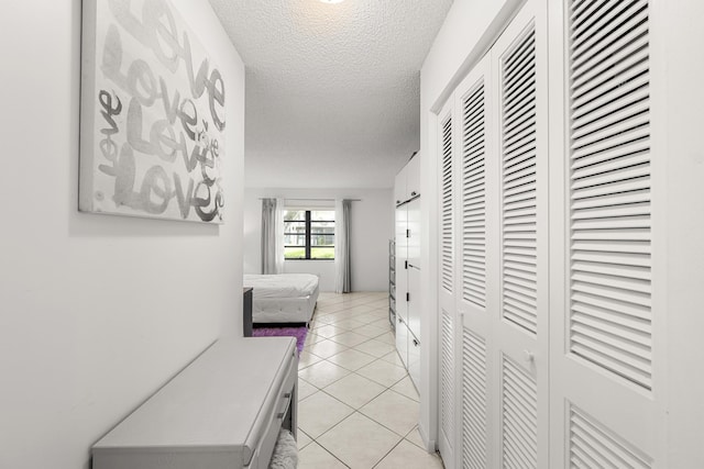 corridor featuring a textured ceiling and light tile patterned flooring