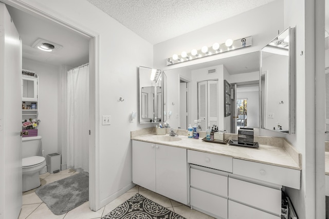 bathroom featuring vanity, a textured ceiling, tile patterned floors, and toilet