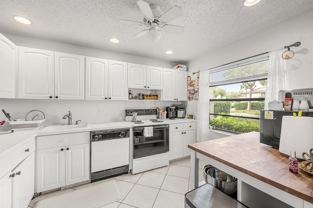 kitchen featuring white cabinetry, sink, light tile patterned floors, white appliances, and a textured ceiling