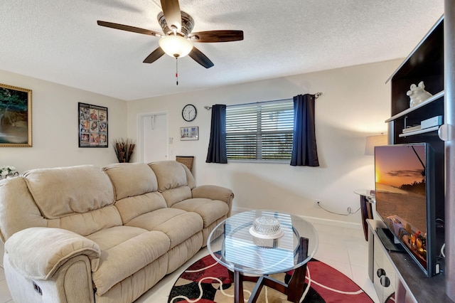 living area featuring a ceiling fan, light tile patterned flooring, a textured ceiling, and baseboards