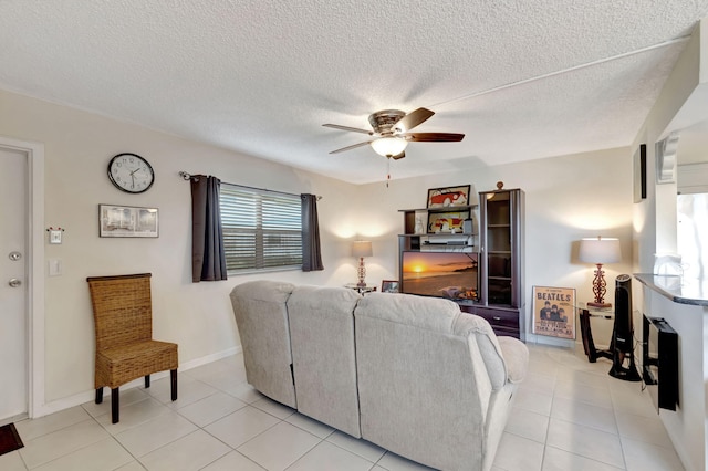 living area featuring ceiling fan, light tile patterned floors, a textured ceiling, and baseboards