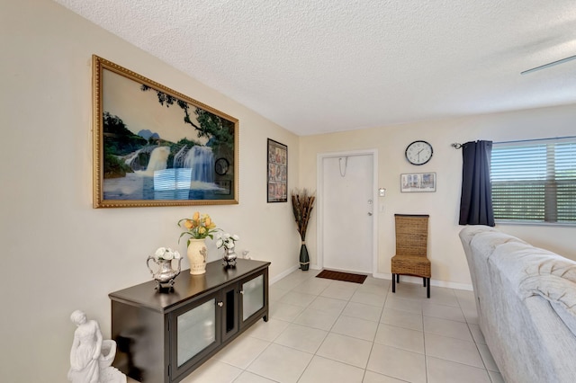 foyer with light tile patterned floors, a textured ceiling, and baseboards