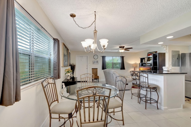 dining space with light tile patterned floors, baseboards, a textured ceiling, and ceiling fan with notable chandelier