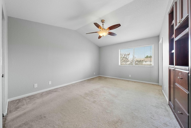 carpeted spare room featuring vaulted ceiling and ceiling fan