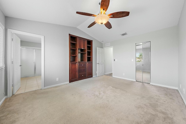 unfurnished bedroom with lofted ceiling, light colored carpet, ceiling fan, and ensuite bath