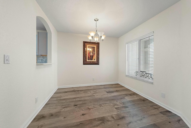 unfurnished dining area with hardwood / wood-style flooring and a chandelier