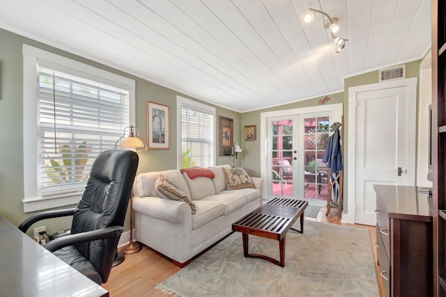 living area with ornamental molding, french doors, visible vents, and light wood-style floors