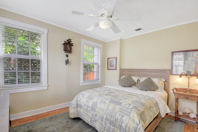 bedroom featuring baseboards, visible vents, a ceiling fan, ornamental molding, and wood finished floors