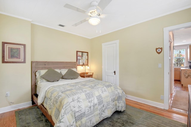 bedroom with baseboards, wood finished floors, visible vents, and crown molding