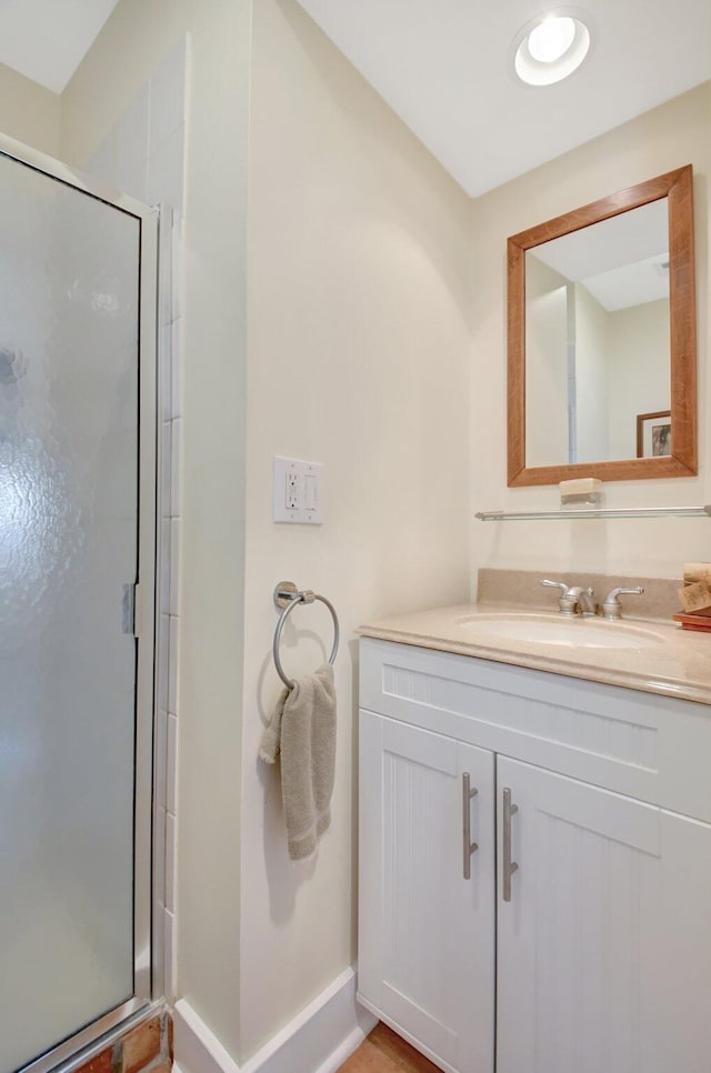 bathroom featuring a stall shower, baseboards, and vanity