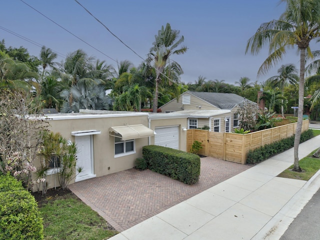 ranch-style house with a garage, fence, and stucco siding