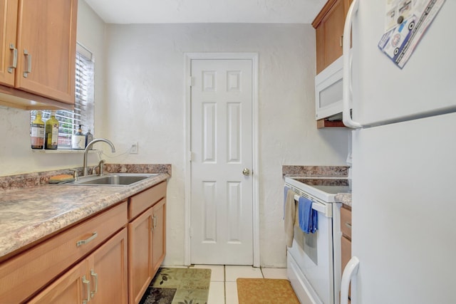 kitchen featuring light tile patterned floors, white appliances, brown cabinetry, and a sink