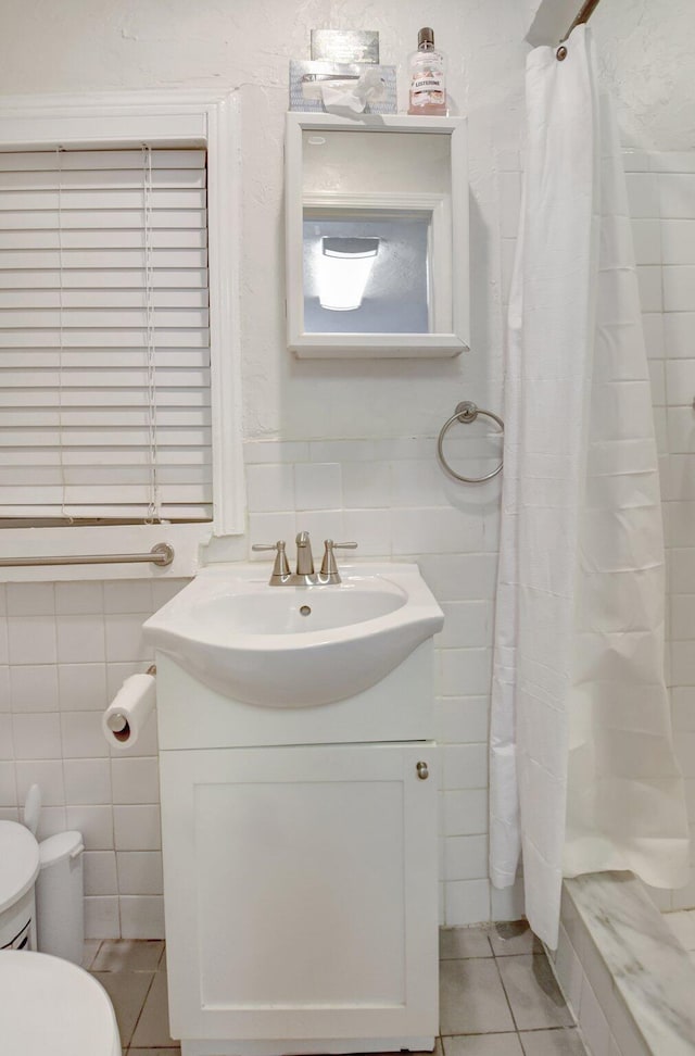 bathroom featuring curtained shower, tile patterned flooring, toilet, vanity, and tile walls