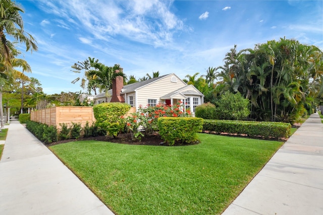 view of front of house with a chimney, fence, and a front lawn