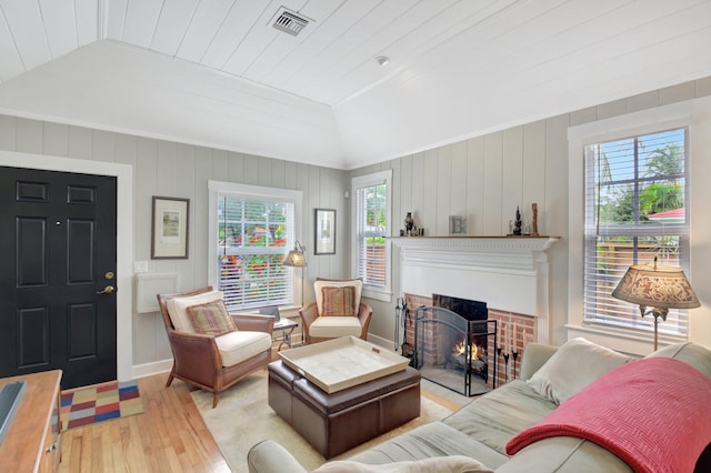 living room featuring lofted ceiling, light wood-style flooring, visible vents, and a wealth of natural light