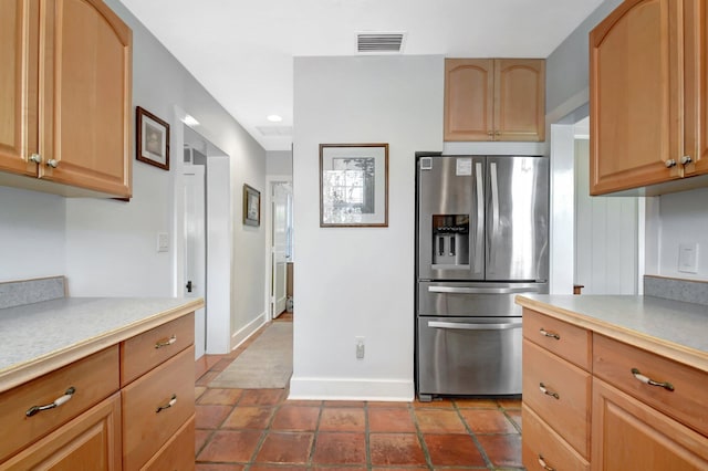 kitchen featuring light countertops, stainless steel fridge, visible vents, and baseboards