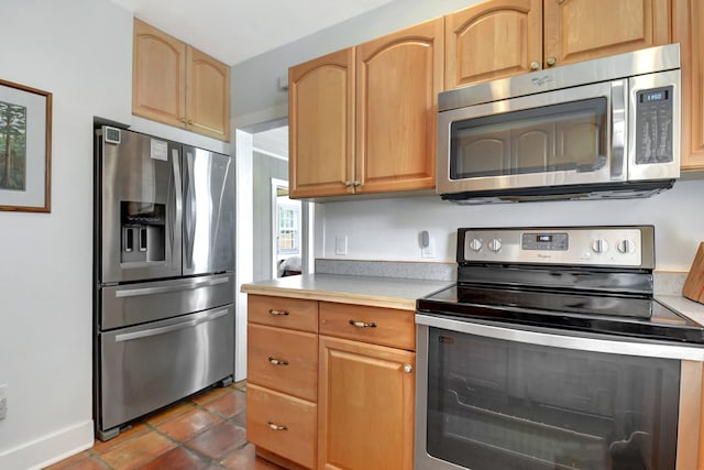 kitchen with baseboards, appliances with stainless steel finishes, light countertops, and dark tile patterned flooring