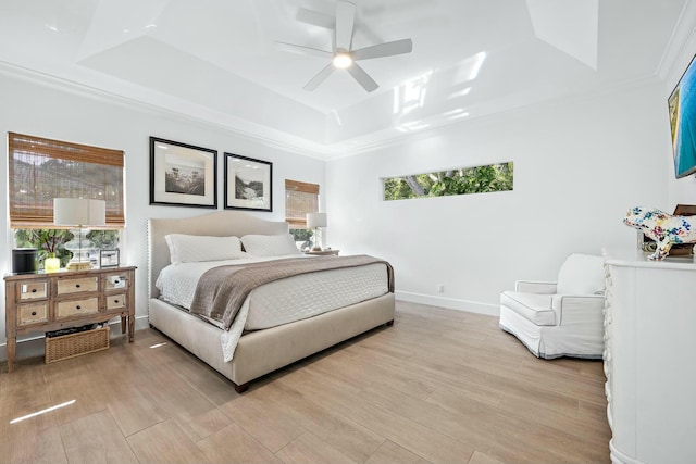 bedroom with crown molding, ceiling fan, a raised ceiling, and light wood-type flooring