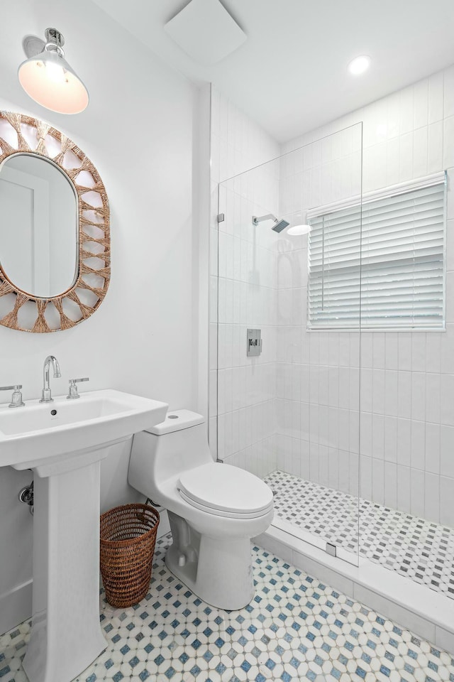 bathroom with a tile shower, sink, and toilet