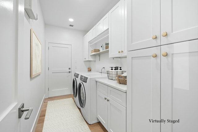 laundry room with cabinets, washer and clothes dryer, and light hardwood / wood-style floors