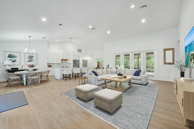 living room featuring an inviting chandelier, high vaulted ceiling, and light wood-type flooring