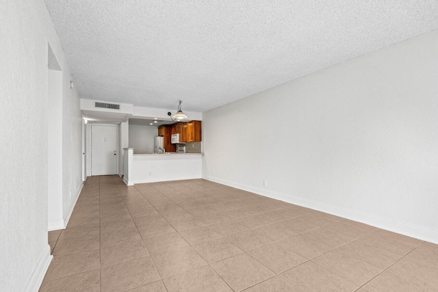 unfurnished living room featuring light tile patterned floors and a textured ceiling