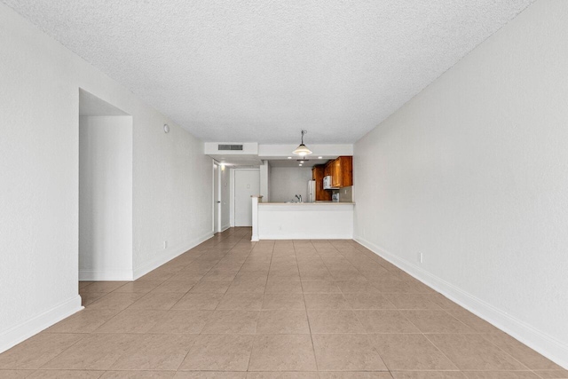 unfurnished living room featuring a textured ceiling and light tile patterned flooring