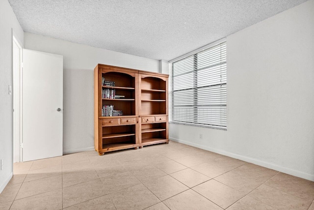 unfurnished room featuring a textured ceiling and light tile patterned floors