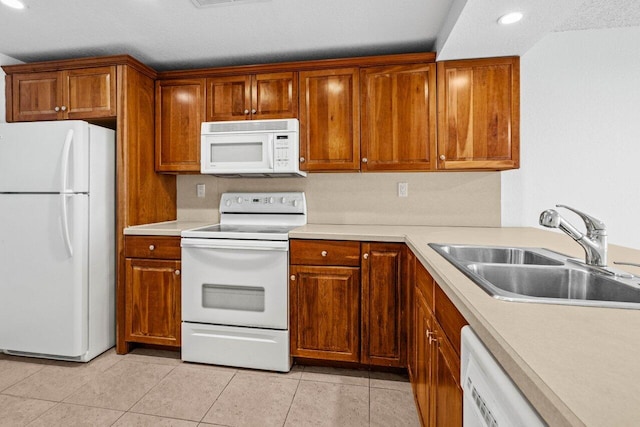 kitchen featuring sink, light tile patterned floors, and white appliances