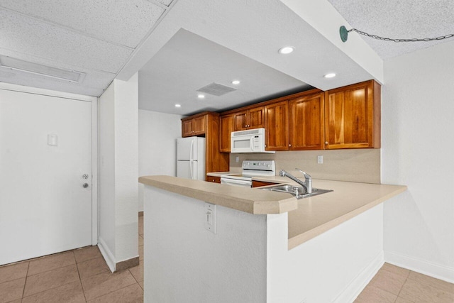 kitchen with sink, white appliances, kitchen peninsula, and light tile patterned flooring