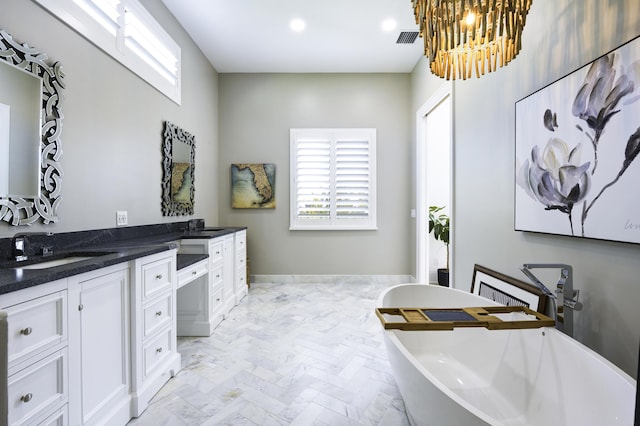 bathroom with recessed lighting, a sink, visible vents, a freestanding bath, and double vanity