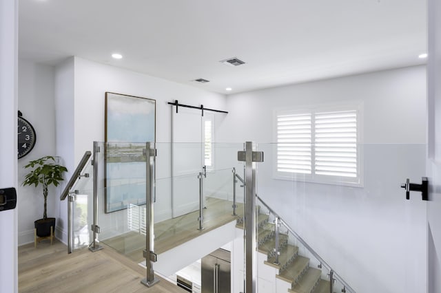 stairway featuring a barn door, baseboards, visible vents, wood finished floors, and recessed lighting