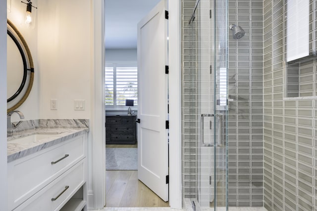 bathroom featuring wood finished floors, a shower stall, and vanity