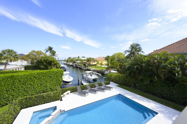 view of pool with a patio, a dock, a water view, and a pool with connected hot tub