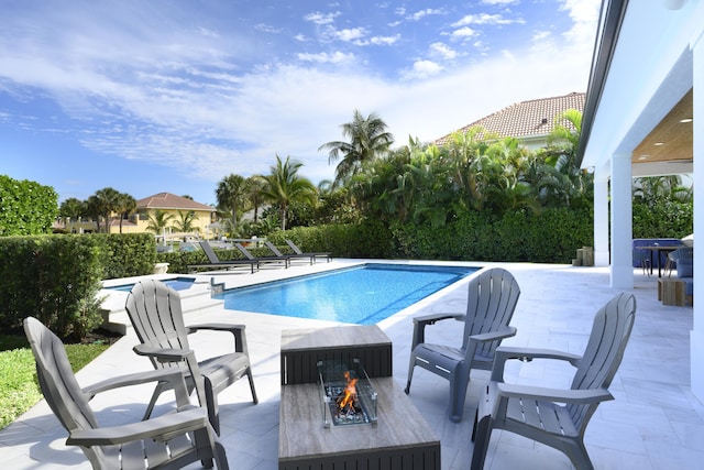 view of swimming pool featuring a fire pit, a fenced in pool, and a patio