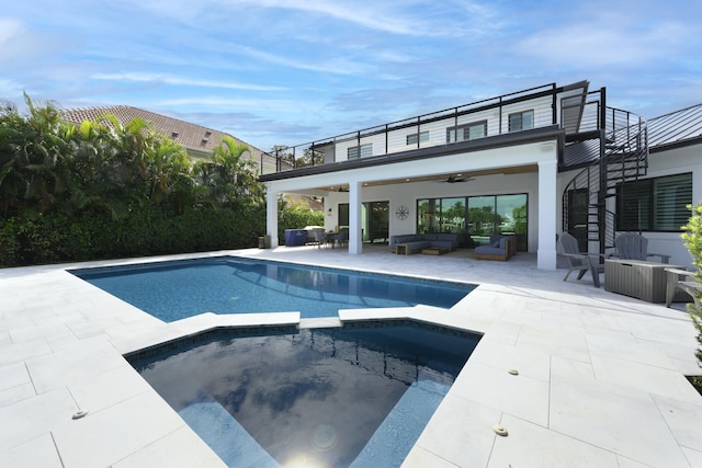 rear view of house featuring a balcony, an outdoor hangout area, a pool with connected hot tub, a ceiling fan, and a patio area