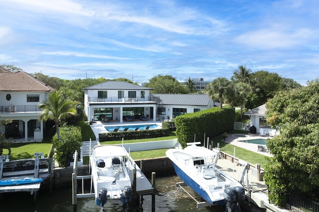 dock area with a patio, boat lift, a balcony, a lawn, and a fenced in pool